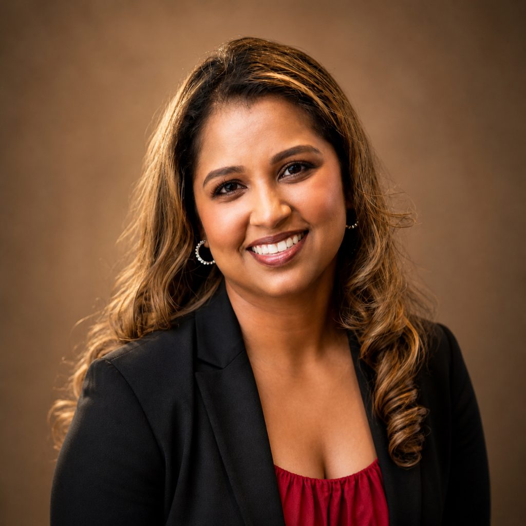woman with long hair smiling at the camera wearing a red shirt and black blazer