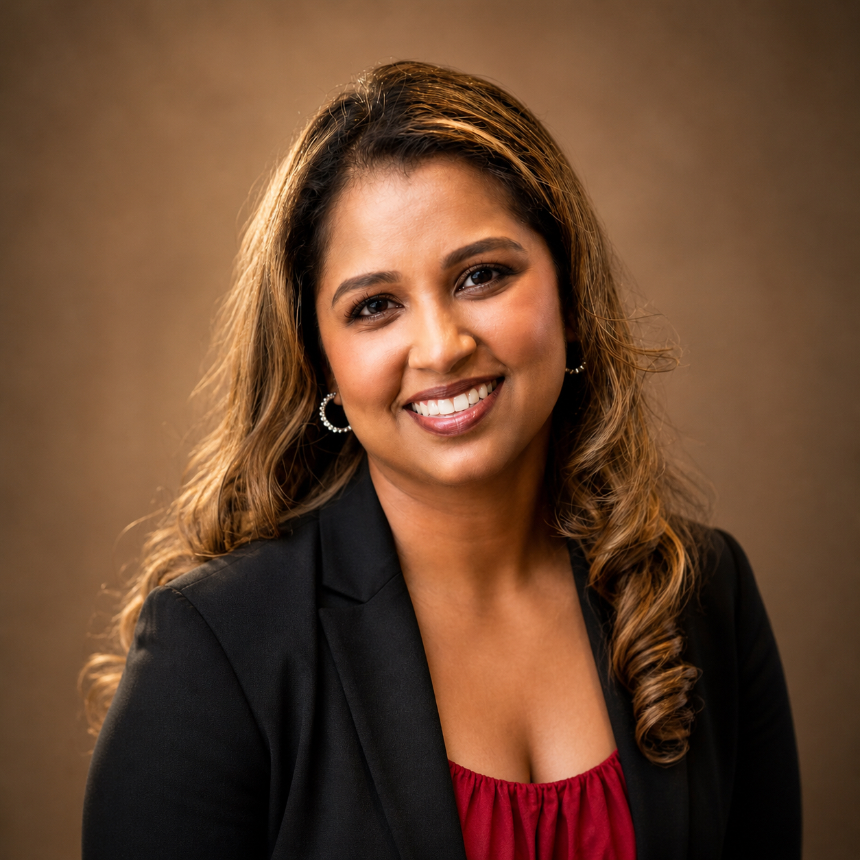 woman with long hair smiling at the camera wearing a red shirt and black blazer