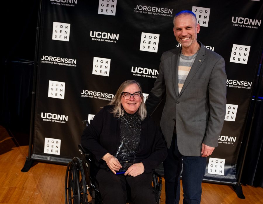 man standing with woman in wheelchair both smiling at camera